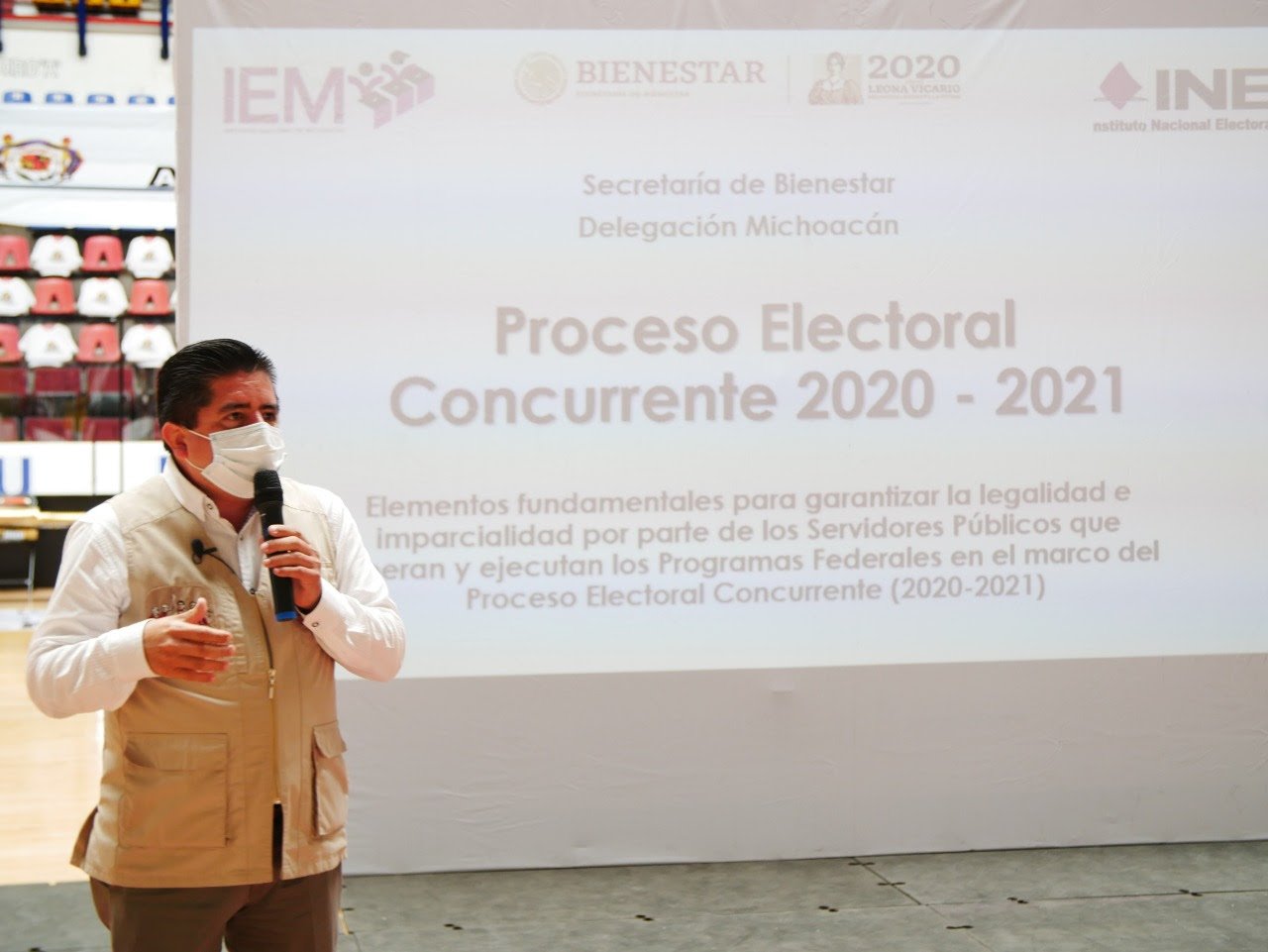 Delegado Roberto Pantioja discursando con una diapositiva proyectada detrás de él con titulos del proceso electoral